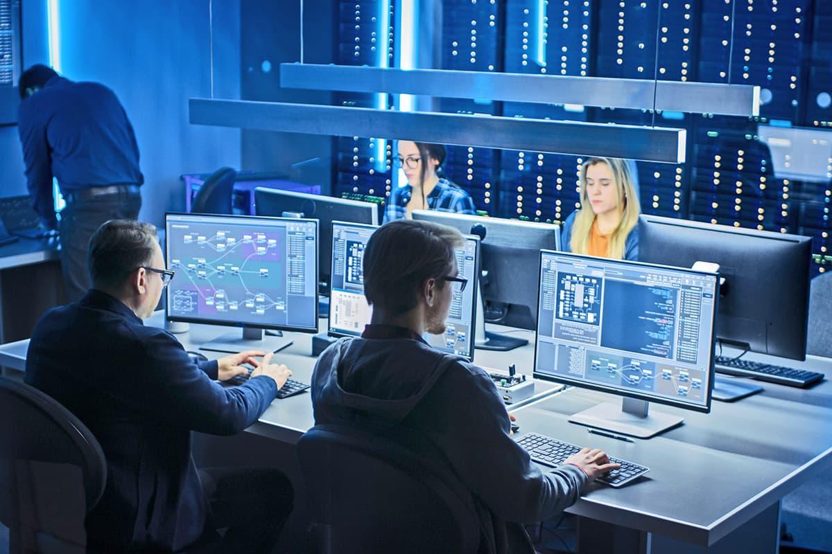 IT professionals working on a bank of computers in a tech lab